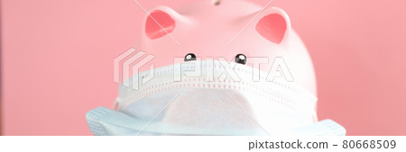 Pink pig piggy bank in protective mask and stethoscope stands on table 80668509