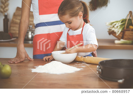 Happy woman and her daughter are kneading the dough and baking cookies for a delicious family feasting. Christmas, New year, Thanksgiving, Anniversary, Mothers Day. Healthy meal cooking concept Happy woman and her daughter are kneading the dough and baking cookies for a delicious family feasting. Christmas, New year, Thanksgiving, Anniversary, Mothers Day. Healthy meal cooking concept 80668957