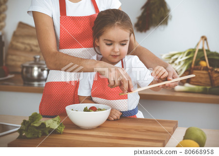 Happy woman and her daughter making healthy vegan salad and snacks for family feasting. Christmas, New year, Thanksgiving, Anniversary, Mothers Day. Healthy meal cooking concept Happy woman and her daughter making healthy vegan salad and snacks for family feasting. Christmas, New year, Thanksgiving, Anniversary, Mothers Day. Healthy meal cooking concept 80668958