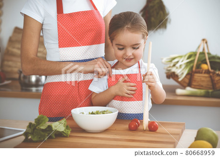Happy woman and her daughter making healthy vegan salad and snacks for family feasting. Christmas, New year, Thanksgiving, Anniversary, Mothers Day. Healthy meal cooking concept Happy woman and her daughter making healthy vegan salad and snacks for family feasting. Christmas, New year, Thanksgiving, Anniversary, Mothers Day. Healthy meal cooking concept 80668959