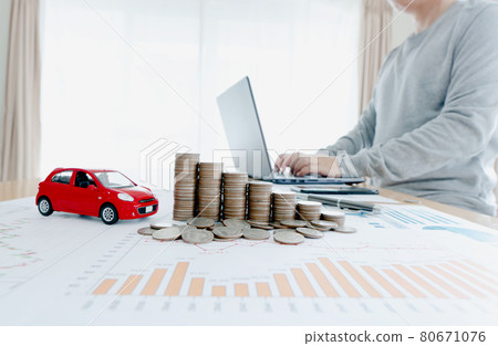Businessman use laptop near the table with stacked of coins and car model , graph and glasses, investment Businessman use laptop near the table with stacked of coins and car model , graph and glasses, investment 80671076