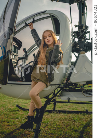 Brown-haired preteen girl standing on footboard of open helicopter 80674323