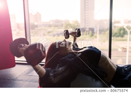 Athletic girl in sportswear performs exercises with barbell, dumbbells. Fitness, healthy lifestyle 80675874