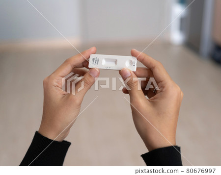 Hand holds a test cartridge at home. COVID-19 Ag rapid self test kits at home in quarantine. Antigen or Antibody test. Virus disease healthcare check. Coronavirus outbreak. 80676997
