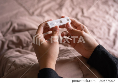 Hand holds a test cartridge at home. COVID-19 Ag rapid self test kits on bed at home in quarantine. Antigen or Antibody test. Virus disease healthcare check. Coronavirus outbreak. Hand holds a test cartridge at home. COVID-19 Ag rapid self test kits on bed at home in quarantine. Antigen or Antibody test. Virus disease healthcare check. Coronavirus outbreak. 80677002