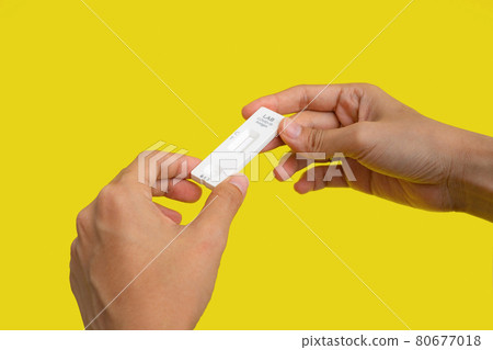 Hand holds a test swab cartridge isolated on yellow. COVID-19 Ag rapid self test kits. Antigen or Antibody test. Virus disease healthcare check. Coronavirus outbreak. 80677018