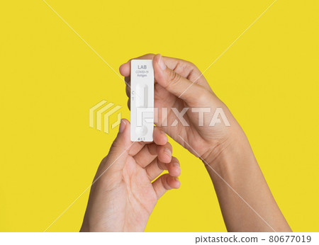 Hand holds a test swab cartridge isolated on yellow. COVID-19 Ag rapid self test kits. Antigen or Antibody test. Virus disease healthcare check. Coronavirus outbreak. 80677019