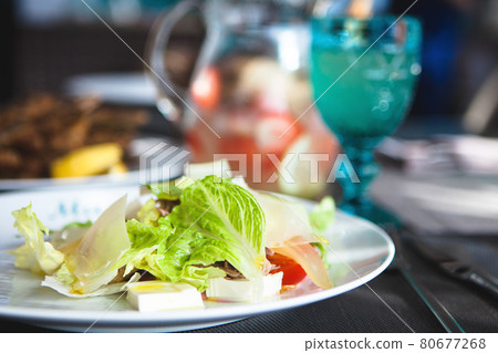 Close up of salad with lettuce, tomatoes and cheese on a white plate Close up of salad with lettuce, tomatoes and cheese on a white plate 80677268