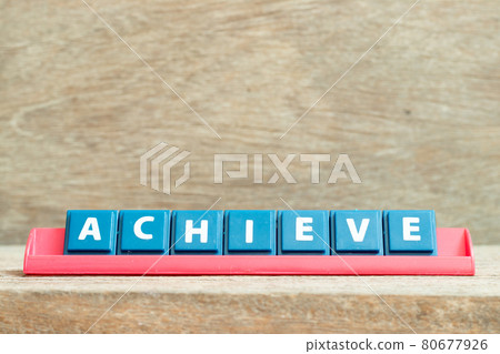 Tile alphabet letter with word achieve in red color rack on wood background Tile alphabet letter with word achieve in red color rack on wood background 80677926