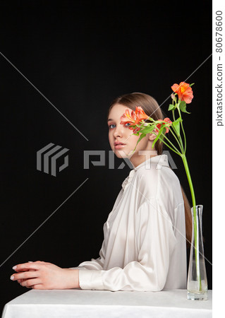 Young woman hiding face behind fresh flowers Young woman hiding face behind fresh flowers 80678600