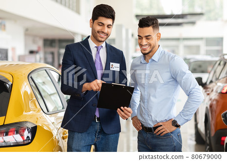 Handsome arab guy having conversation with sales assistant in showroom Handsome arab guy having conversation with sales assistant in showroom 80679000