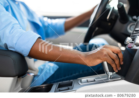 Unrecognizable black man driving new car in city 80679280