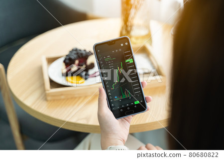 Woman is checking Bitcoin price chart on digital exchange on smartphone in the cafe 80680822