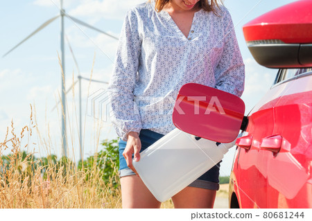 Woman filling a diesel exhaust fluid or petrol on the background of wind turbines. Green energy against environmental pollution. Woman filling a diesel exhaust fluid or petrol on the background of wind turbines. Green energy against environmental pollution. 80681244