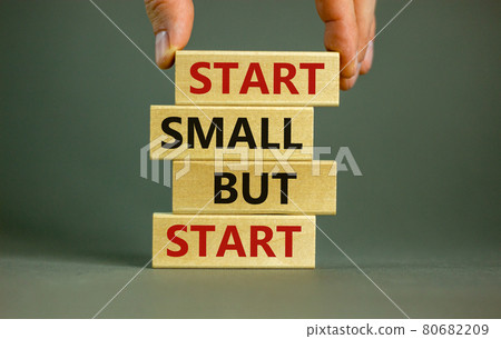 Start small but start symbol. Concept words 'Start small but start' on wooden blocks on a beautiful grey background. Businessman hand. Business, motivational concept. 80682209