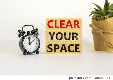 Clear your space symbol. Wooden blocks with words 'Clear your space'. Beautiful white background, black alarm clock, house plant. Business, clear your space concept, copy space. 80682241