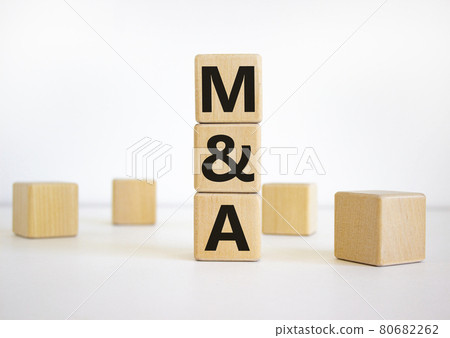 Mergers and acquisitions symbol. Concept words 'M and A - Mergers and acquisitions' on wooden cubes on a beautiful white background. Business, mergers and acquisitions concept. Copy space. 80682262