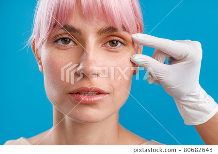 Hand of beautician touching female face, examining it before giving botox injection 80682643