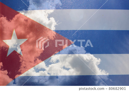 Cuba flag in hand on blue sky with clouds Cuba flag in hand on blue sky with clouds 80682901