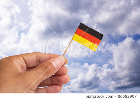 Small germany flag in hand on blue sky background 80682907
