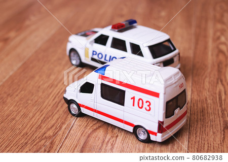 Toy ambulances and police cars on wooden floor 80682938