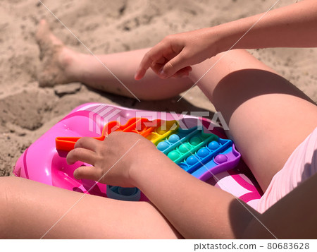 Little girl plays with cotton on the beach. A modern toy for toddlers. Antistress toy Little girl plays with cotton on the beach. A modern toy for toddlers. Antistress toy 80683628