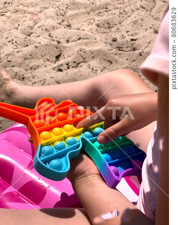 Little girl plays with cotton on the beach. A modern toy for toddlers. Antistress toy Little girl plays with cotton on the beach. A modern toy for toddlers. Antistress toy 80683629