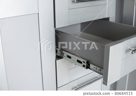 Stainless telescopic bayonet drawer slide guides, installed on a kitchen cabinet from gray chipboard. Accessories for carpentry used in the construction of furniture. Custom kitchen installation. Stainless telescopic bayonet drawer slide guides, installed on a kitchen cabinet from gray chipboard. Accessories for carpentry used in the construction of furniture. Custom kitchen installation. 80684515