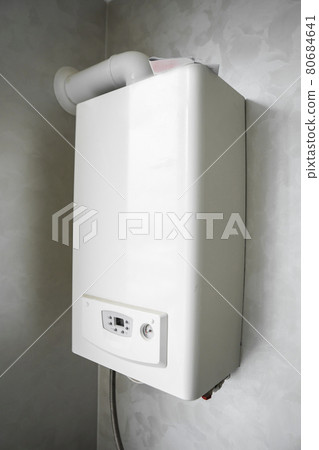 White modern home gas boiler mounted on a grey wall on a kitchen. Water heater. Water heating, ecology. White modern home gas boiler mounted on a grey wall on a kitchen. Water heater. Water heating, ecology. 80684641