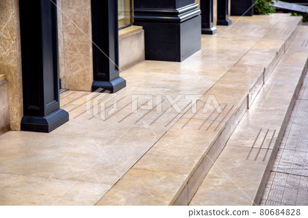 doorstep of beige glossy marble floor covering on the porch in the entrance to the store with black wooden columns on the facade of the building close-up of architectural design, nobody. 80684828