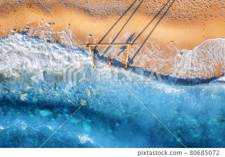Aerial view of woman on the swing, beautiful blue sea with waves Aerial view of woman on the swing, beautiful blue sea with waves 80685072