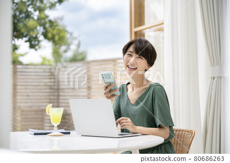 Image of female worcation remote work heading to a laptop on the terrace Image of female worcation remote work heading to a laptop on the terrace 80686263