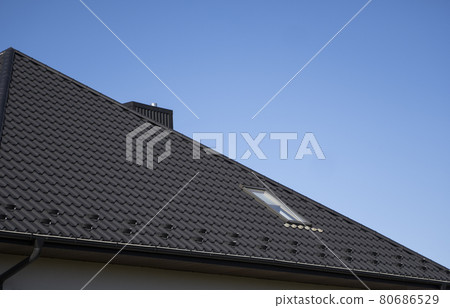 Brown corrugated metal profile roof installed on a modern house. The roof of corrugated sheet. Roofing of metal profile wavy shape. Modern roof made of metal. Metal roofing. Brown corrugated metal profile roof installed on a modern house. The roof of corrugated sheet. Roofing of metal profile wavy shape. Modern roof made of metal. Metal roofing. 80686529