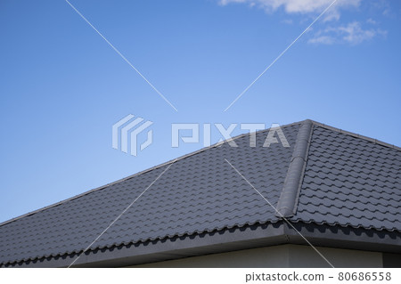 Brown corrugated metal profile roof installed on a modern house. The roof of corrugated sheet. Roofing of metal profile wavy shape. Modern roof made of metal. Metal roofing. 80686558