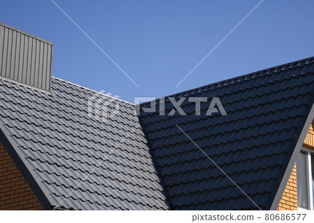 Grey corrugated metal profile roof installed on a modern house. The roof of corrugated sheet. Roofing of metal profile wavy shape. Modern roof made of metal. Metal roofing. 80686577