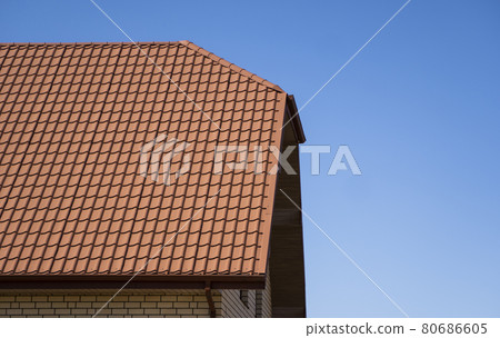 Red corrugated metal profile roof installed on a modern house. The roof of corrugated sheet. Roofing of metal profile wavy shape. Modern roof made of metal. Metal roofing. 80686605