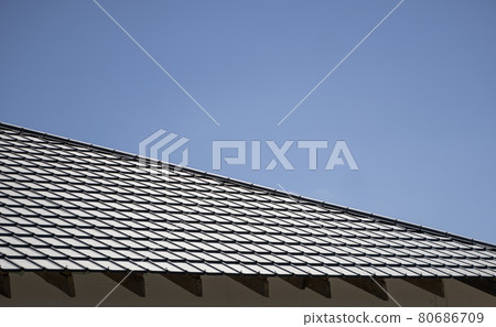 Brown corrugated metal profile roof installed on a modern house. The roof of corrugated sheet. Roofing of metal profile wavy shape. Modern roof made of metal. Metal roofing. 80686709