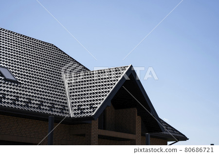 Brown corrugated metal profile roof installed on a modern house with a attic windows. The roof of corrugated sheet. Roofing of metal profile wavy shape. Modern roof made of metal. Metal roofing. 80686721
