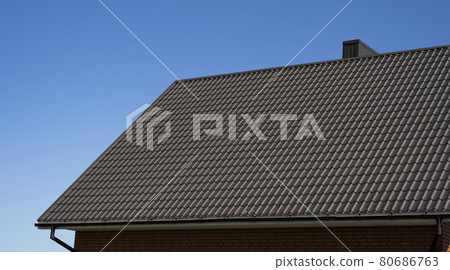 Brown corrugated metal profile roof installed on a modern house. The roof of corrugated sheet. Roofing of metal profile wavy shape. Modern roof made of metal. Metal roofing. Brown corrugated metal profile roof installed on a modern house. The roof of corrugated sheet. Roofing of metal profile wavy shape. Modern roof made of metal. Metal roofing. 80686763