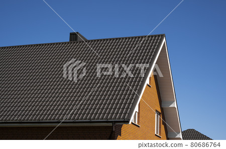 Brown corrugated metal profile roof installed on a modern house. The roof of corrugated sheet. Roofing of metal profile wavy shape. Modern roof made of metal. Metal roofing. 80686764