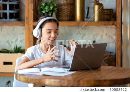 Photo of a schoolgirl during an online lesson. She does her homework online and answers the teacher's questions. 80688522