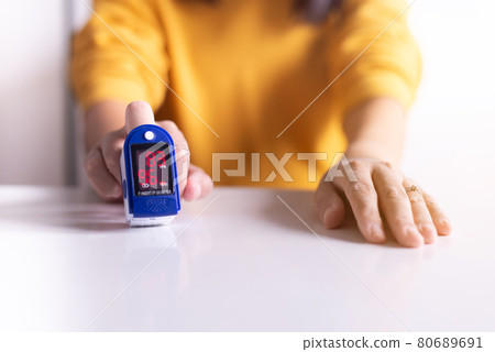 Patient woman using fingertip pulse oximeter oxygen saturation meter SPO2 PR blood monitor finger at home 80689691