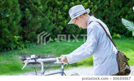Senior man pushing a bicycle and going out Senior man pushing a bicycle and going out 80689867