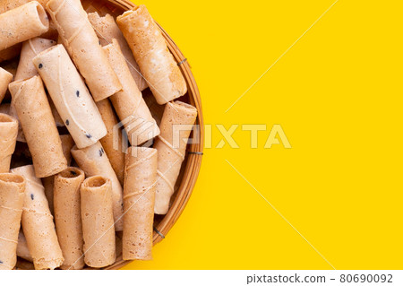 Thai crispy coconut rolls in bamboo basket on yellow background. Thai crispy coconut rolls in bamboo basket on yellow background. 80690092