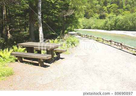 A bench placed at a superb view point on the promenade facing the Azusa River in the fresh green of Shinshu Kamikochi 80690897