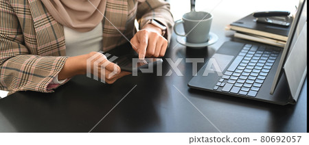 Cropped shot of muslim businesswoman in hijab using mobile phone at office workplace. 80692057