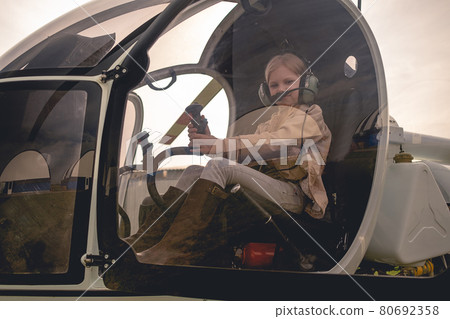 View through glass of cockpit of tween girl imitating helicopter control 80692358
