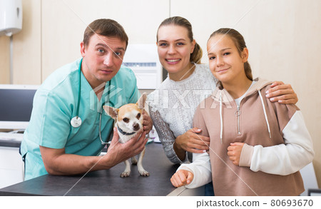 Portrait of happy mother and daughter consulting by professional veterinarian about their dog health 80693670