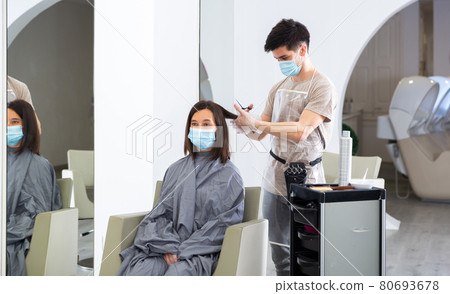 Woman client in mask during cuts hair at beauty salon Woman client in mask during cuts hair at beauty salon 80693678