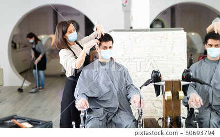 Client in mask during hair cut by professional hairdresser in mask Client in mask during hair cut by professional hairdresser in mask 80693794